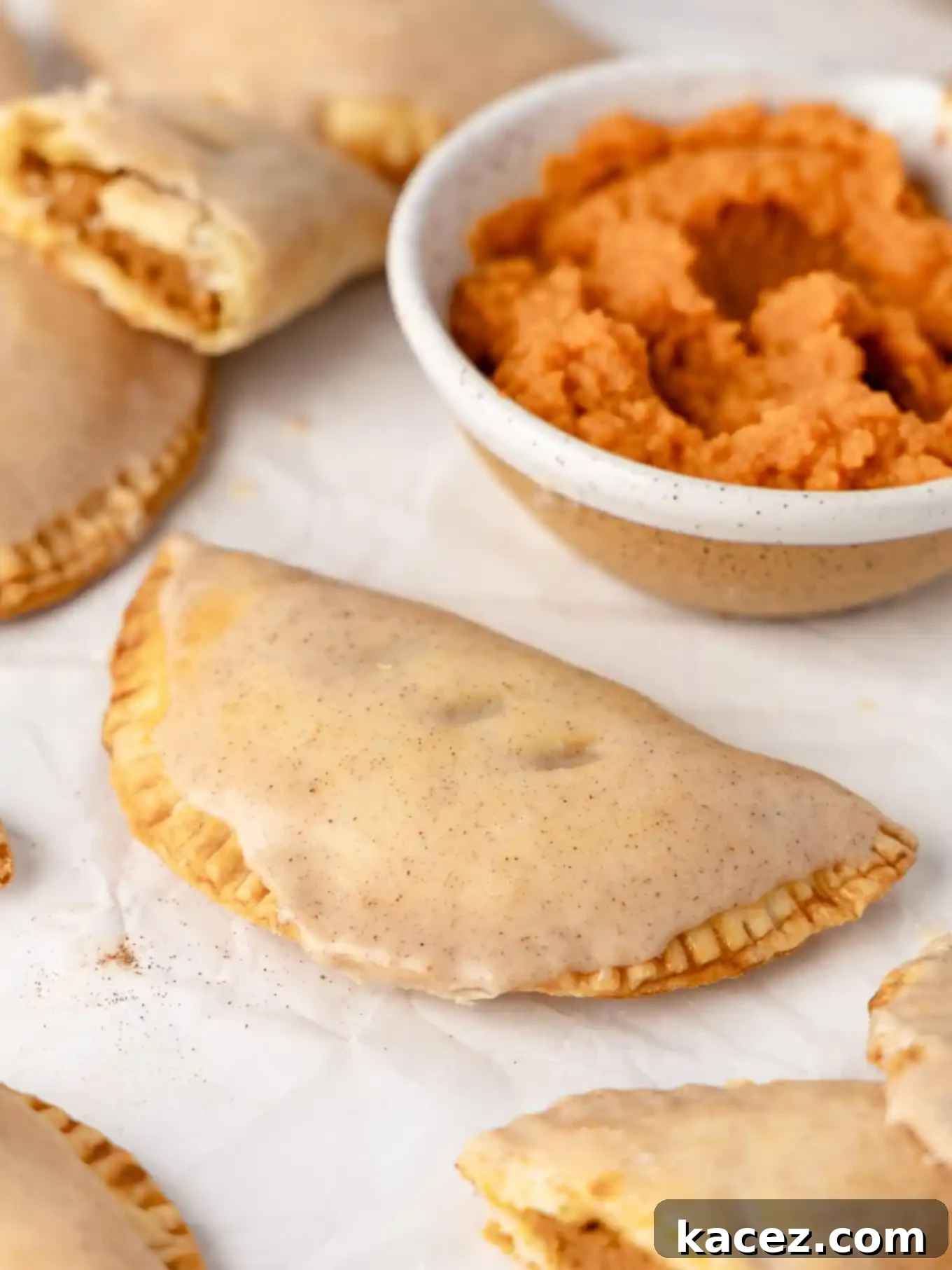 Spiced Pumpkin Pastries 11 A glazed pumpkin hand pie placed next to a small bowl of pumpkin puree, highlighting the main ingredient.