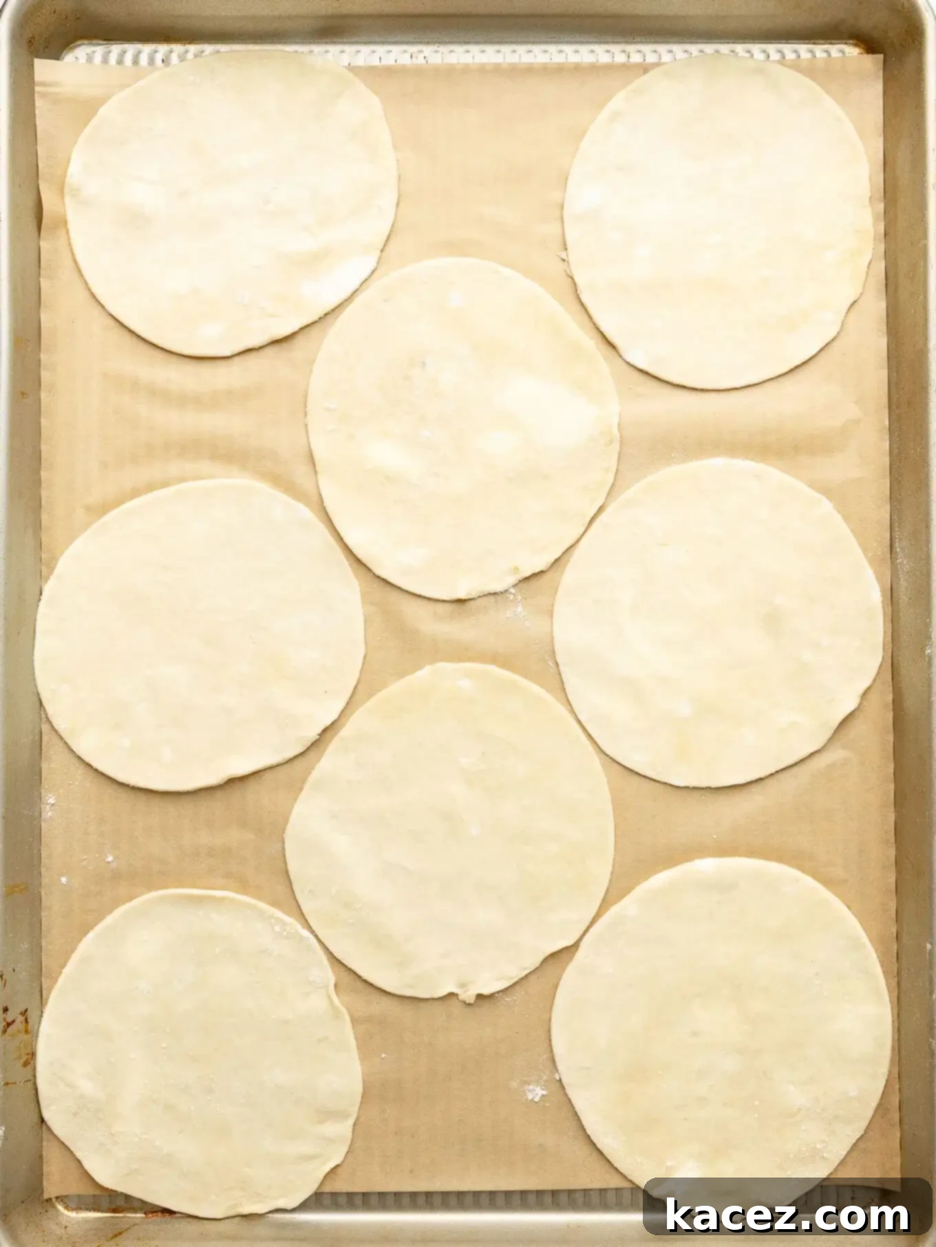 Spiced Pumpkin Pastries 5 Circles of pie dough neatly arranged on a lined baking sheet, ready for filling.