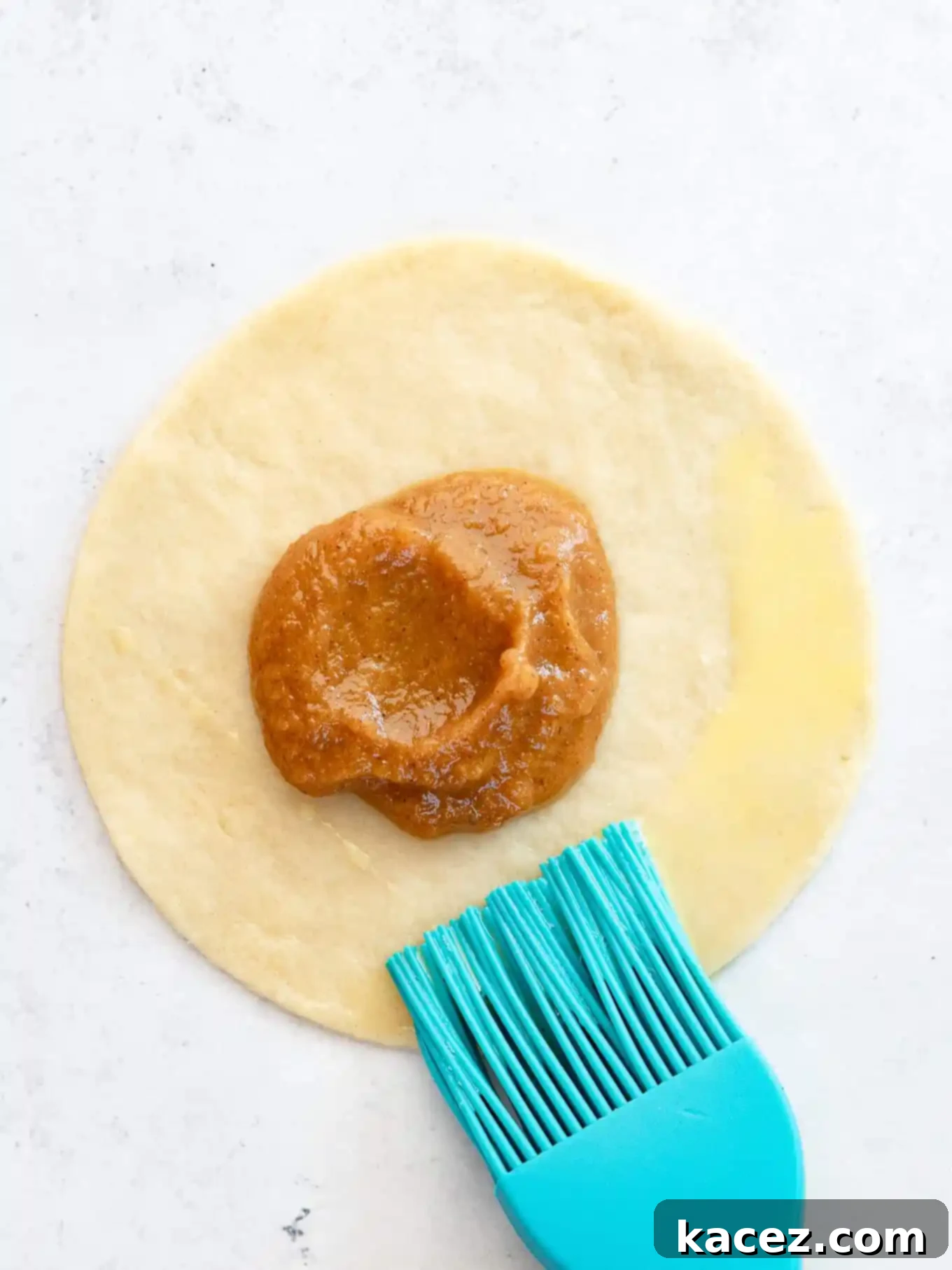 Spiced Pumpkin Pastries 6 A circle of pie dough filled with spiced pumpkin pie filling and brushed with egg wash on one half.