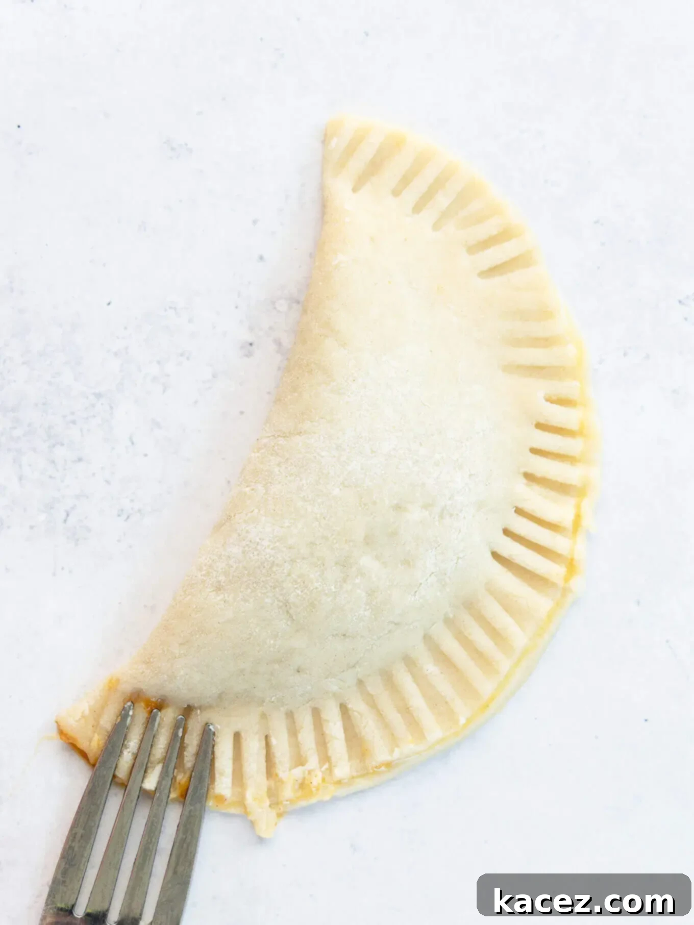 Spiced Pumpkin Pastries 7 A pumpkin hand pie, crimped shut with a fork, ready for baking.