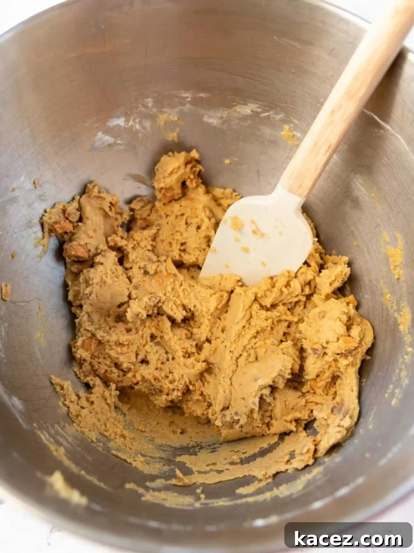 Sweet & Crunchy Butterfinger Treats 5 An overhead view of the completed peanut butter cookie dough, studded with Butterfinger pieces, resting in the bowl of a stand mixer, ready for scooping.