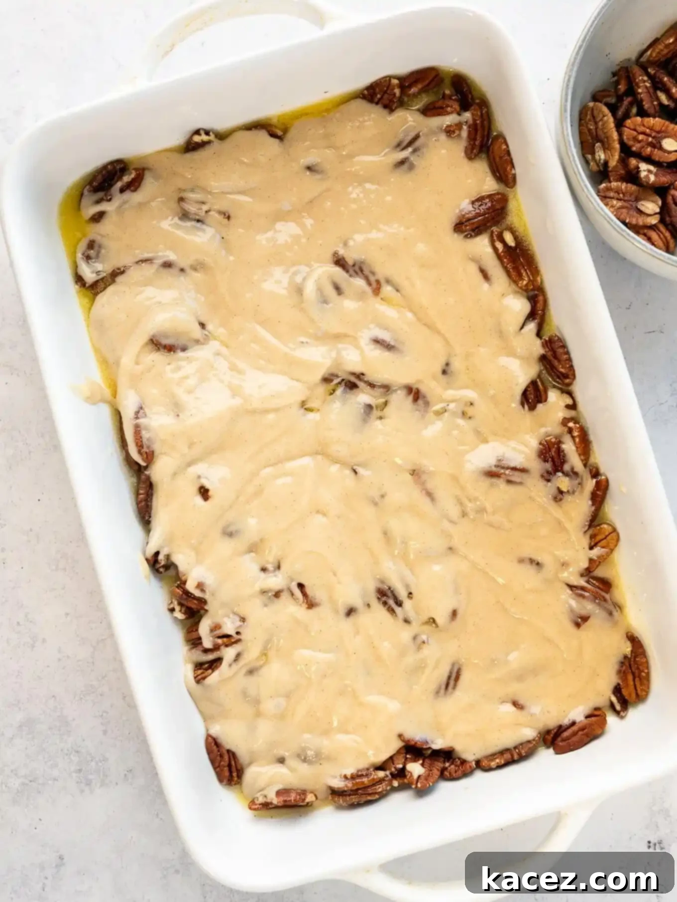 Pecan Cobbler Delight 5 An overhead view of pecans generously topped with a smooth batter in a baking dish, ready for the next layer of flavor.