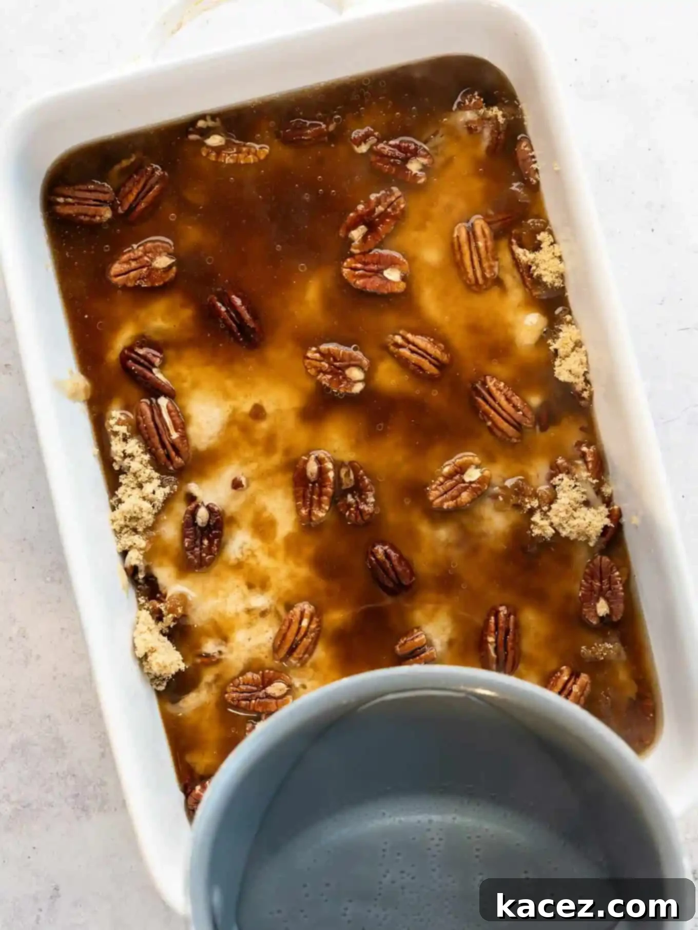 Pecan Cobbler Delight 6 A gentle stream of water being carefully poured into a baking dish filled with pecans and batter, creating the magic of the self-saucing cobbler.