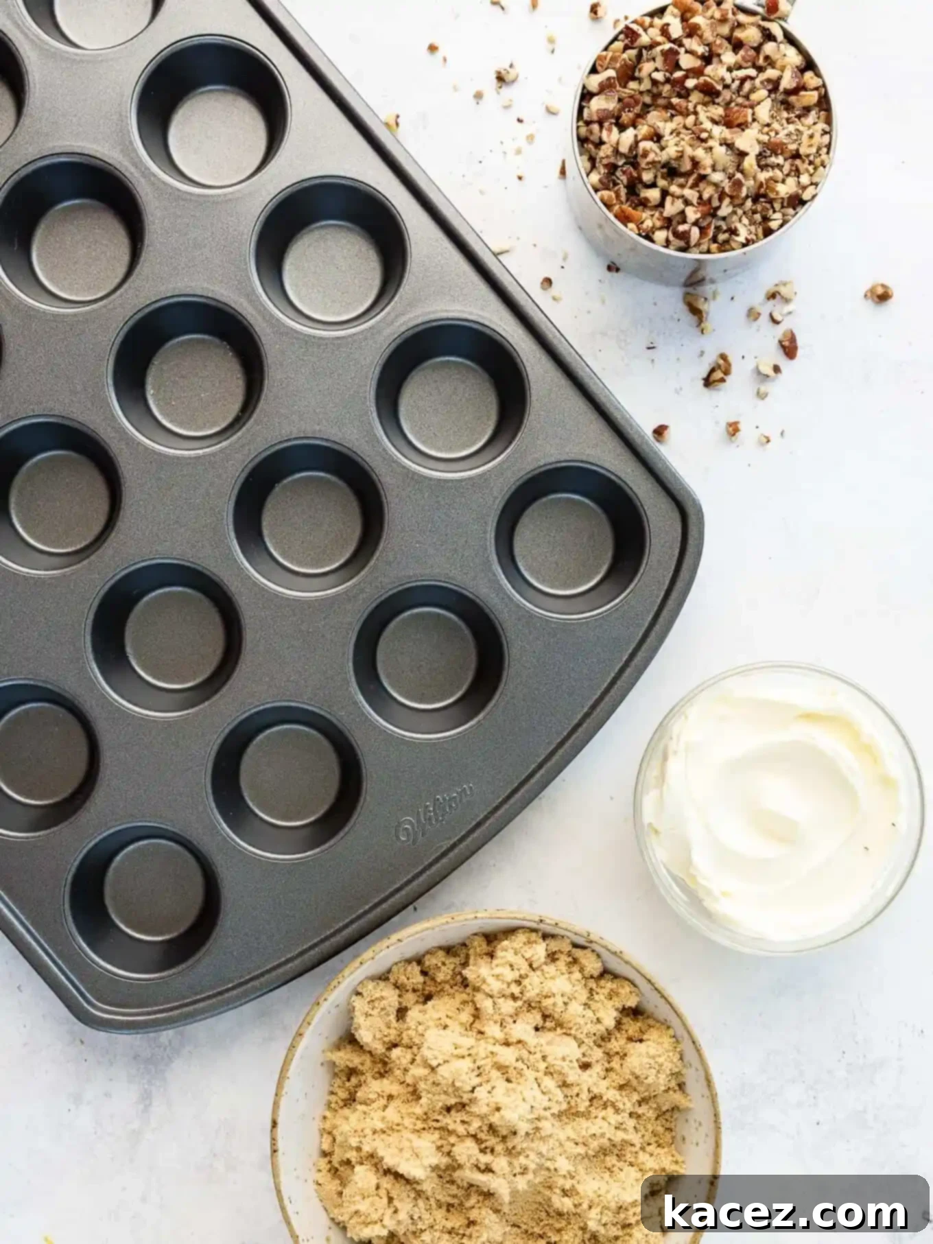 Bite-Sized Pecan Perfection 3 An overhead flat lay of essential pecan tassie ingredients: freshly chopped pecans, a block of cream cheese, rich brown sugar, and a mini muffin pan ready for baking.