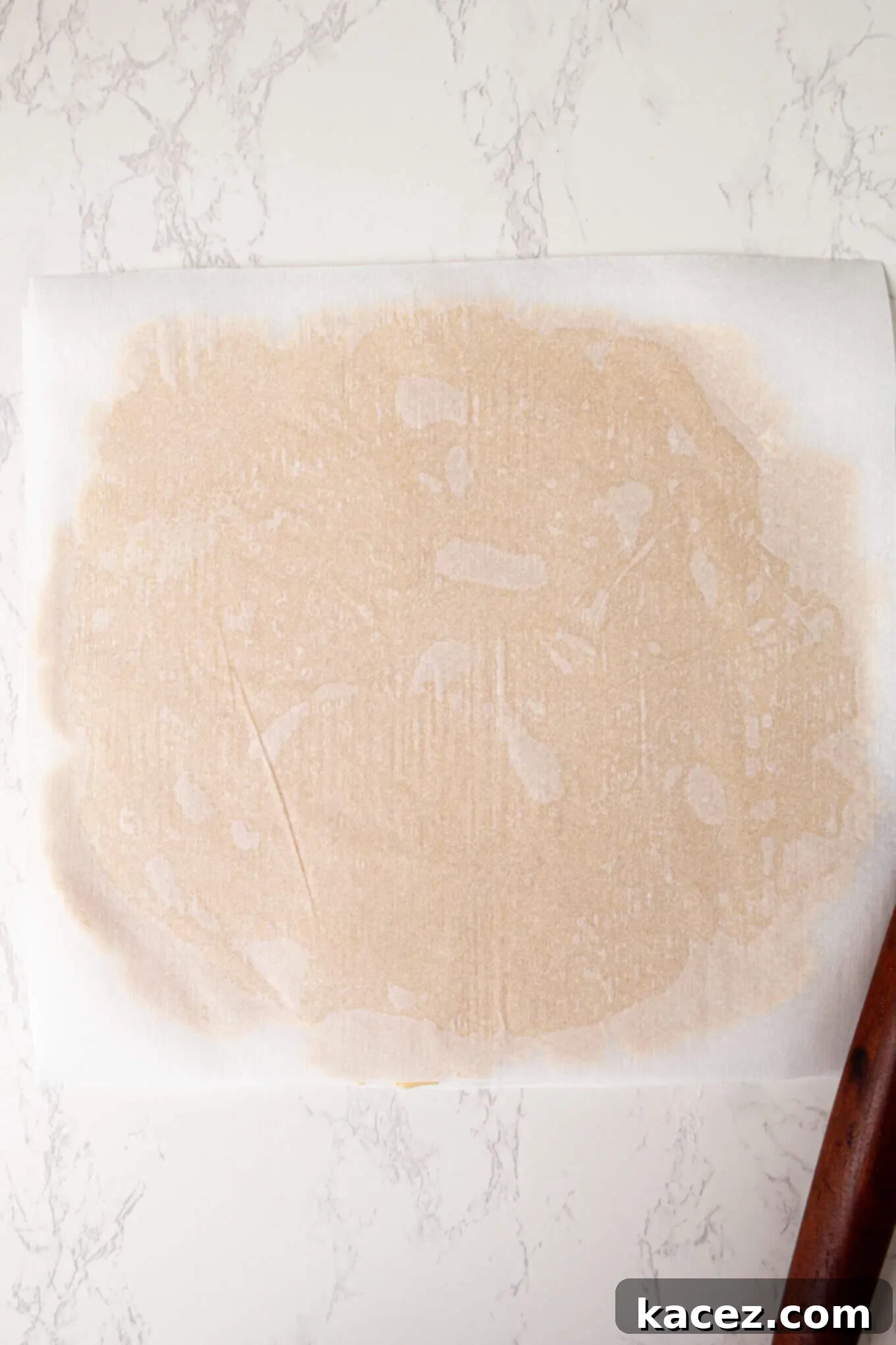 Sugar cookie dough rolled out evenly between two sheets of parchment paper, ready to be cut into festive shapes.