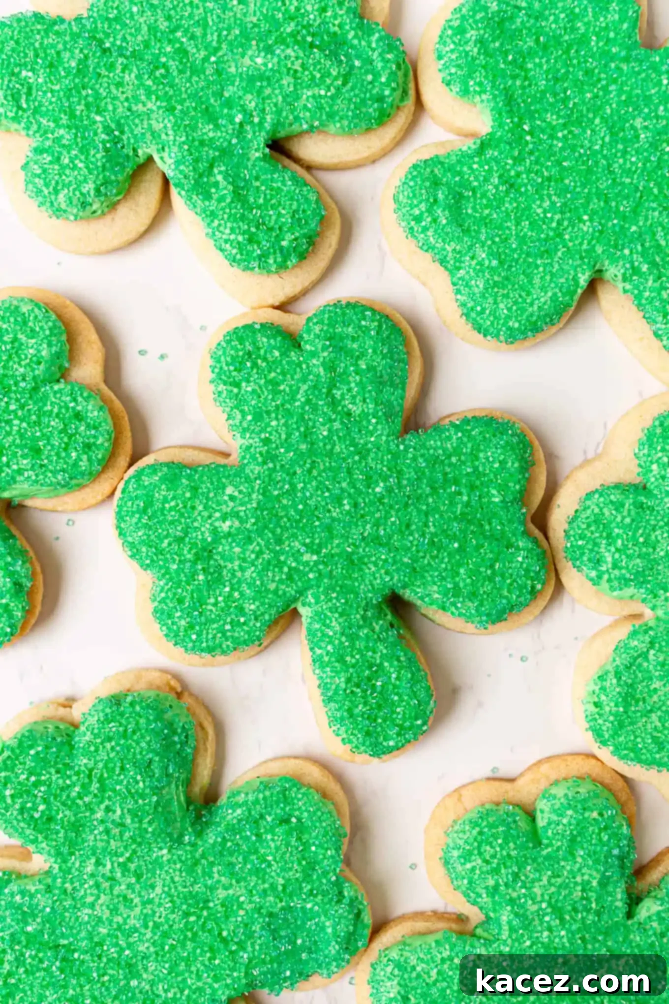 A batch of freshly decorated cut-out shamrock sugar cookies generously covered in vibrant green sanding sugar, ready to bring St. Patrick's Day cheer.