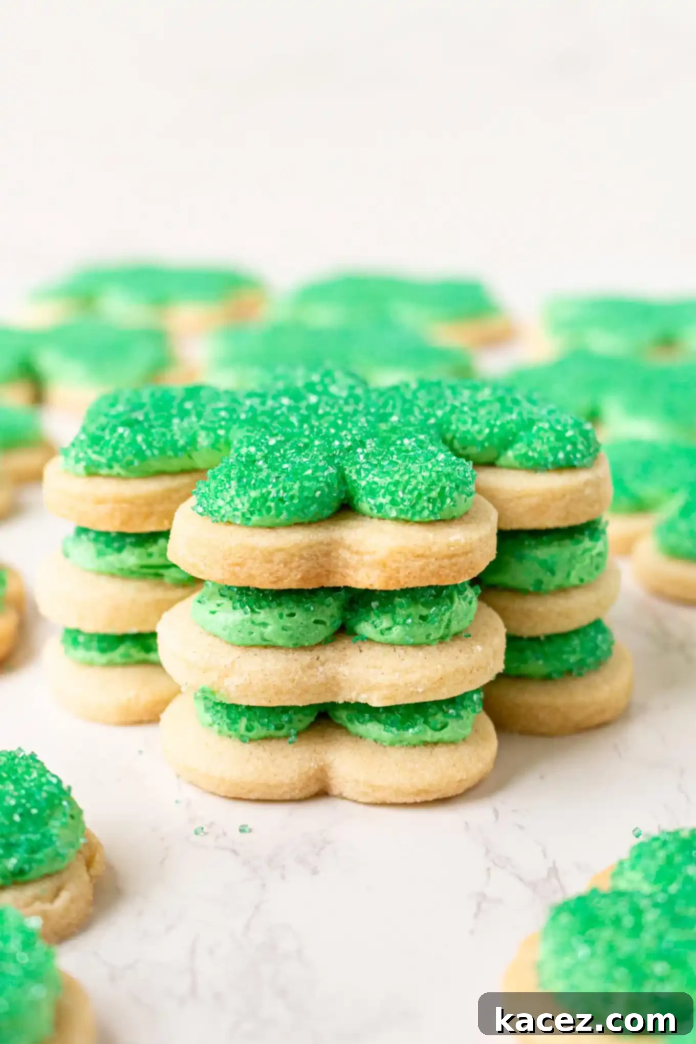 A neatly stacked tower of three delicious shamrock cookies, showcasing the soft texture and inviting green color, perfect for a St. Patrick's Day celebration.